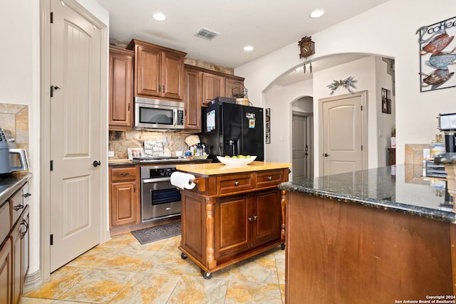 kitchen featuring light tile patterned floors, tasteful backsplash, a kitchen island, and stainless steel appliances