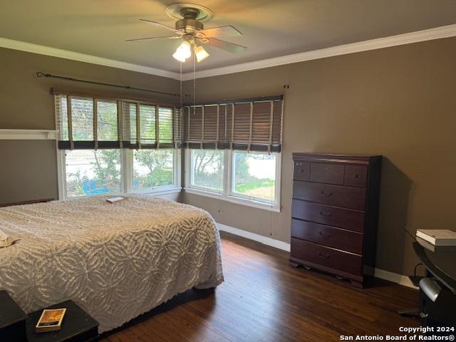 bedroom with ornamental molding and dark hardwood / wood-style flooring