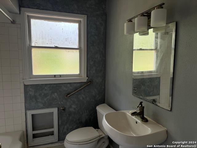 full bathroom featuring washtub / shower combination, plenty of natural light, toilet, and sink