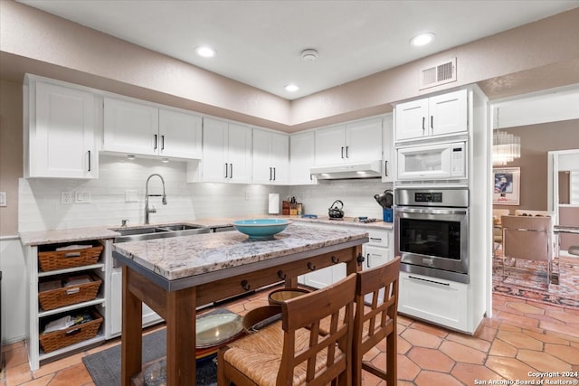 kitchen featuring appliances with stainless steel finishes, sink, backsplash, light tile patterned flooring, and white cabinetry