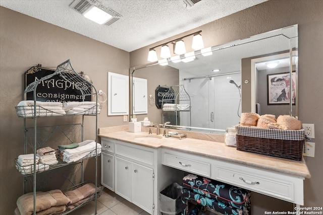 bathroom featuring tile patterned flooring, walk in shower, vanity, and a textured ceiling