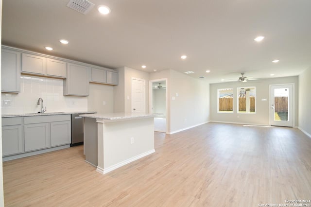 kitchen with sink, backsplash, gray cabinets, and a kitchen island