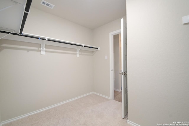 walk in closet with light colored carpet