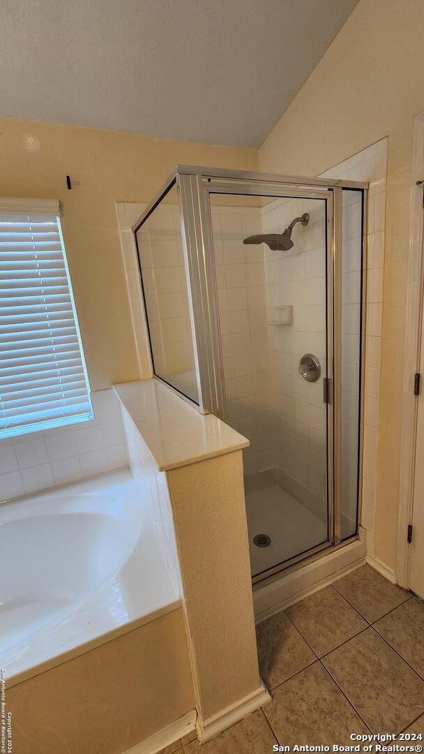 bathroom featuring tile patterned flooring, a garden tub, and a shower stall