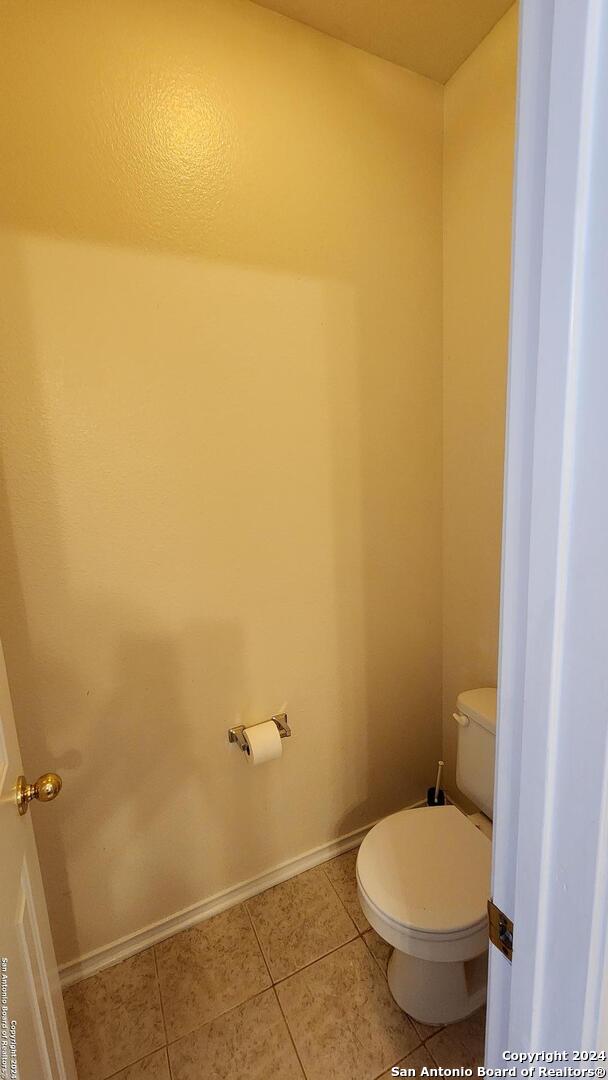 bathroom featuring tile patterned flooring, baseboards, and toilet