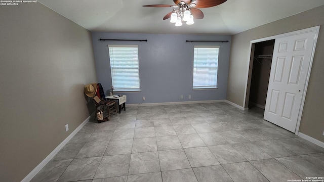 unfurnished bedroom with ceiling fan, light tile patterned floors, a closet, and baseboards