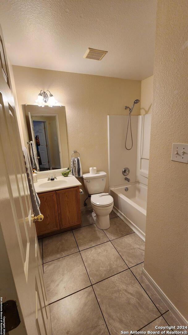 bathroom featuring shower / bathtub combination, toilet, a textured ceiling, and visible vents