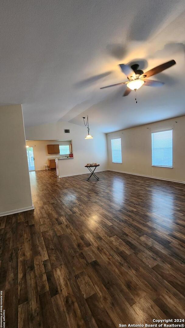 unfurnished living room featuring dark wood-style floors, ceiling fan, visible vents, and baseboards