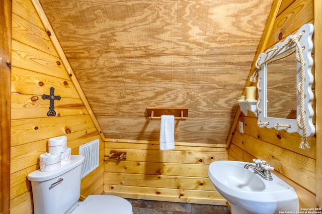 bathroom featuring toilet, sink, and wood walls