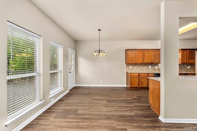 kitchen with backsplash, a chandelier, hanging light fixtures, and dark hardwood / wood-style floors