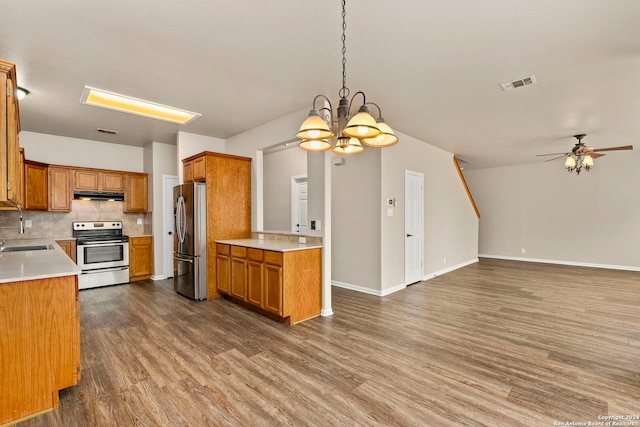 kitchen with stainless steel appliances, hanging light fixtures, dark wood-type flooring, and decorative backsplash