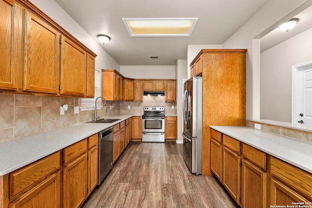 kitchen with sink, stainless steel appliances, hardwood / wood-style floors, and tasteful backsplash