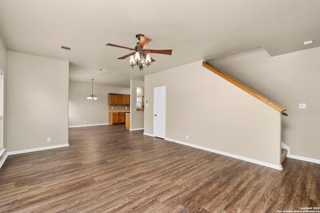 unfurnished living room with ceiling fan with notable chandelier and dark hardwood / wood-style flooring