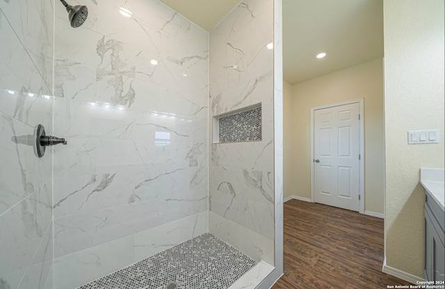 bathroom featuring hardwood / wood-style flooring, tiled shower, and vanity