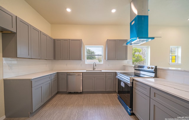 kitchen featuring sink, appliances with stainless steel finishes, gray cabinetry, island exhaust hood, and decorative backsplash