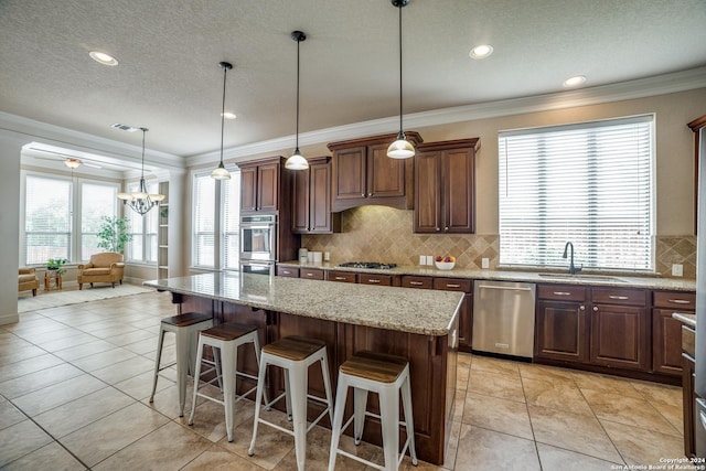 kitchen featuring light tile patterned flooring, sink, a center island, hanging light fixtures, and appliances with stainless steel finishes