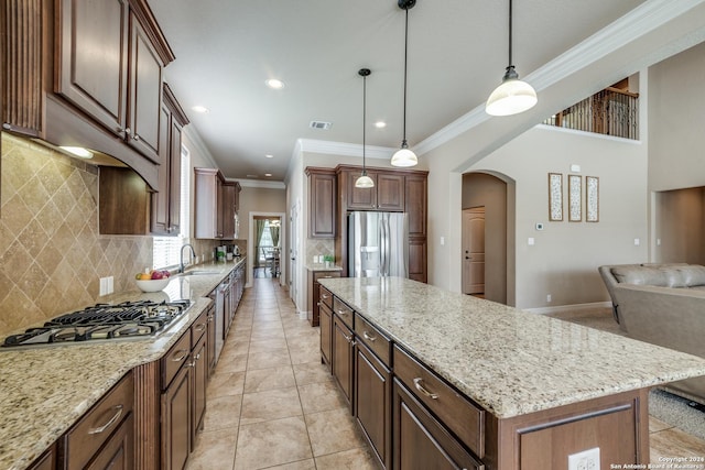 kitchen featuring appliances with stainless steel finishes, a center island, decorative backsplash, and decorative light fixtures