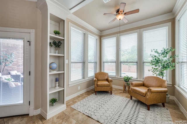 sitting room with built in shelves, ceiling fan, ornamental molding, and light tile patterned floors