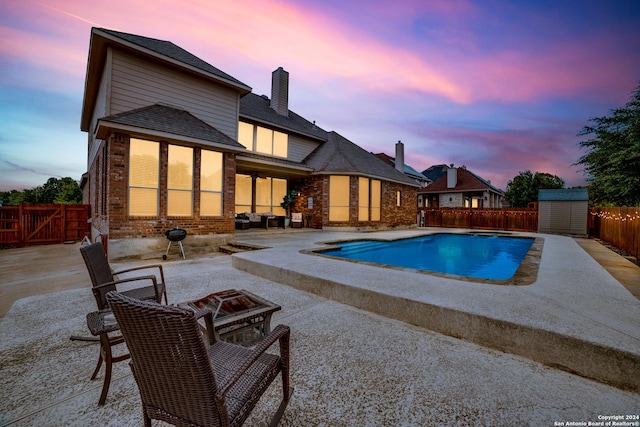 pool at dusk featuring a shed and a patio