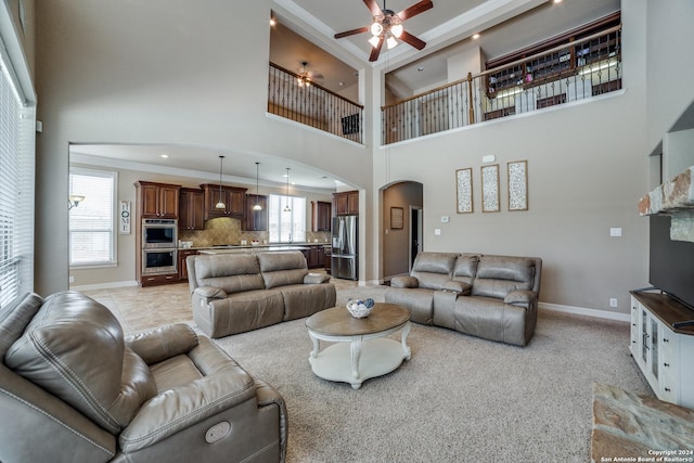 living room with ceiling fan, a towering ceiling, ornamental molding, and a wealth of natural light