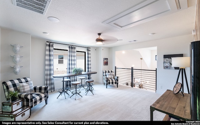 sitting room featuring a textured ceiling, light colored carpet, and ceiling fan