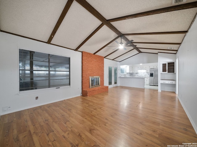 unfurnished living room featuring light hardwood / wood-style flooring, a textured ceiling, lofted ceiling, brick wall, and ceiling fan