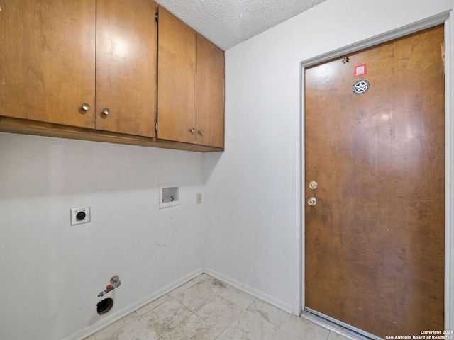 laundry area featuring gas dryer hookup, cabinets, hookup for a washing machine, a textured ceiling, and light tile patterned floors