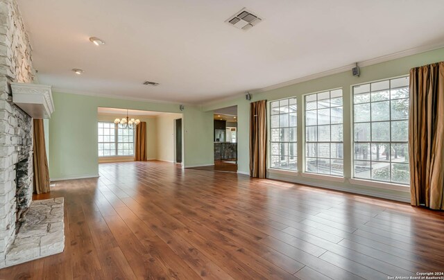 unfurnished living room featuring a fireplace, wood-type flooring, a chandelier, and plenty of natural light