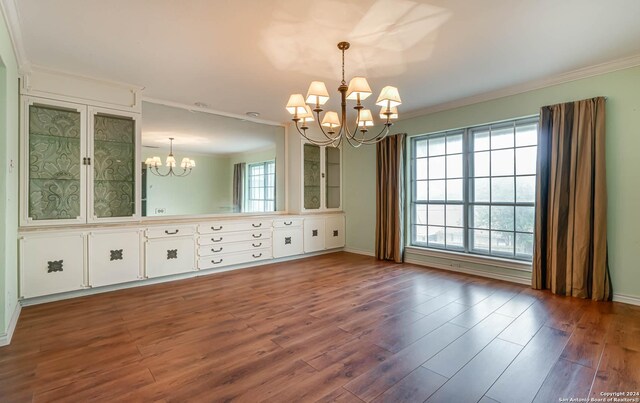 unfurnished dining area featuring an inviting chandelier, ornamental molding, hardwood / wood-style flooring, and a healthy amount of sunlight