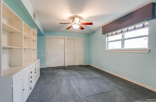 unfurnished bedroom with multiple closets, ceiling fan, and dark carpet