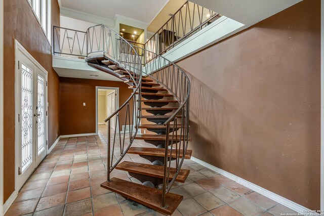 staircase with ornamental molding, light tile patterned floors, french doors, and a towering ceiling