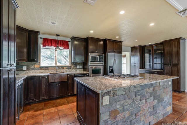 kitchen featuring sink, appliances with stainless steel finishes, tasteful backsplash, and dark tile patterned floors