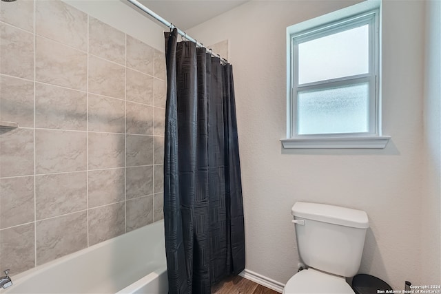 bathroom featuring hardwood / wood-style floors, shower / tub combo with curtain, and toilet