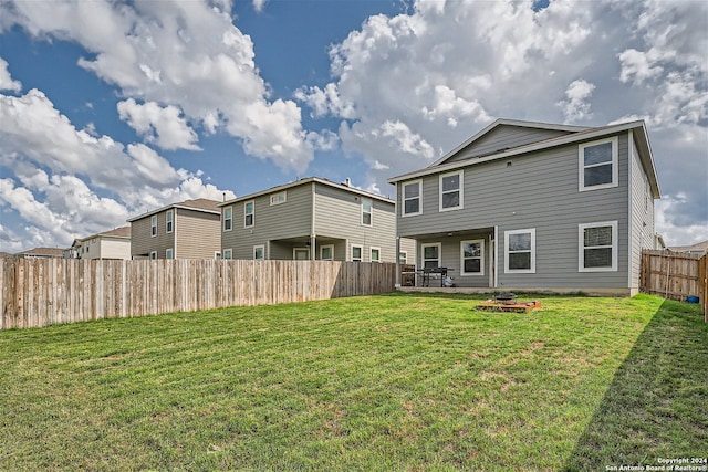 back of property featuring a fire pit and a lawn