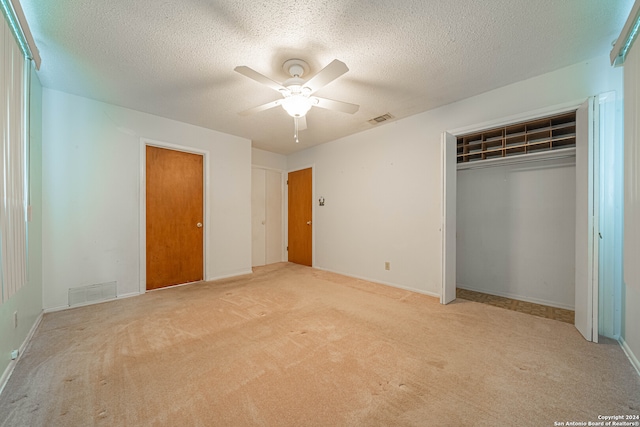 unfurnished bedroom with light carpet, a closet, a textured ceiling, and ceiling fan