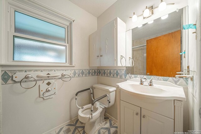 bathroom with tile patterned flooring, a bidet, a textured ceiling, toilet, and vanity