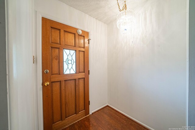 entryway with a notable chandelier, hardwood / wood-style floors, and a textured ceiling