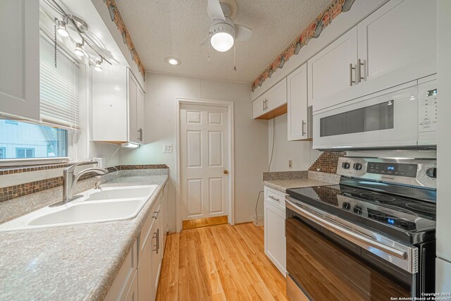 kitchen featuring light wood-type flooring, white cabinets, ceiling fan, stainless steel range with electric cooktop, and sink