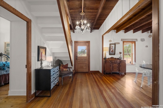 entrance foyer featuring wooden ceiling, a chandelier, hardwood / wood-style floors, and lofted ceiling with beams