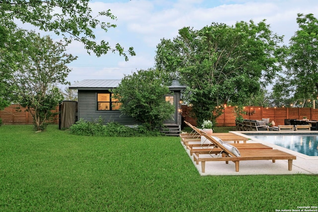 back of house with a lawn, an outbuilding, and a fenced in pool