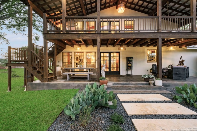 rear view of house featuring a wooden deck, french doors, and a patio