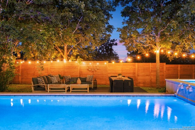 pool at dusk featuring an in ground hot tub, a lawn, and a patio