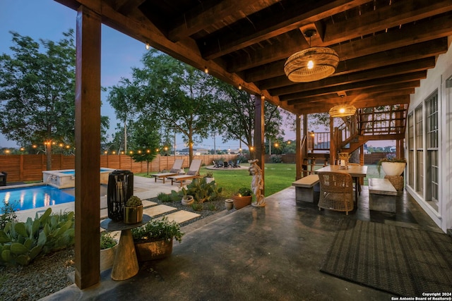 patio terrace at dusk with a fenced in pool and a yard