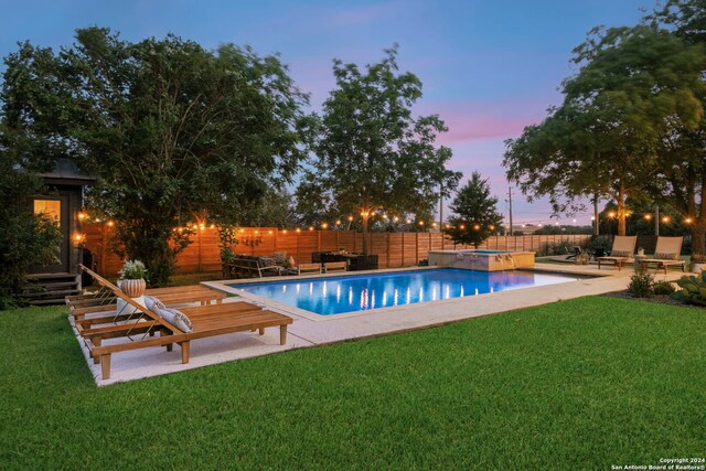 pool at dusk featuring an in ground hot tub and a patio