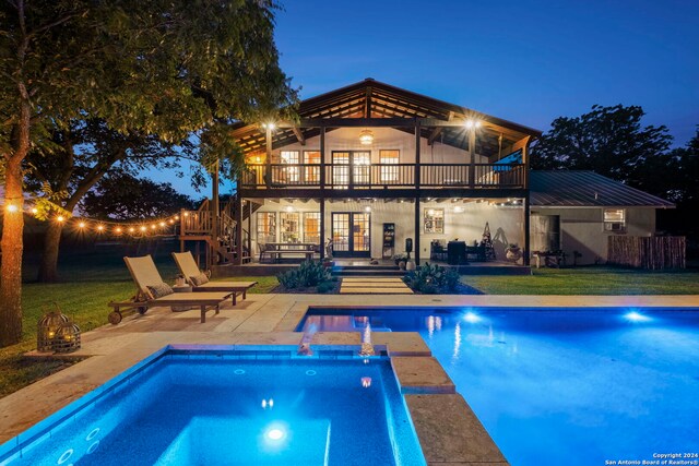 pool at dusk featuring a lawn, a patio, and an in ground hot tub