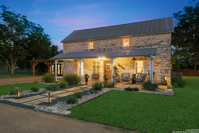 pool at dusk with a hot tub, pool water feature, and a patio