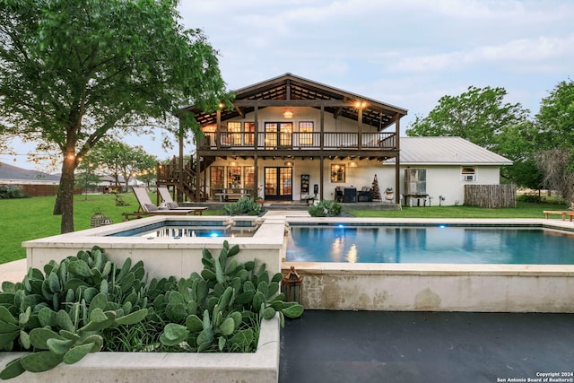 rear view of house with a swimming pool with hot tub, a patio area, and a lawn