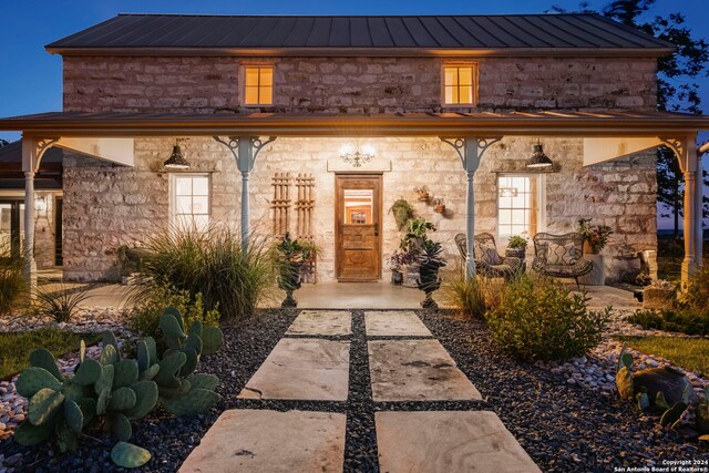 back house at dusk with a lawn, french doors, a balcony, and a patio