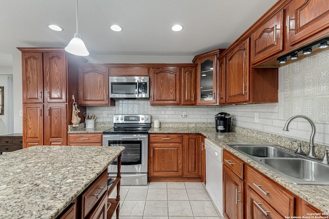 kitchen featuring sink, stainless steel appliances, tasteful backsplash, light stone countertops, and decorative light fixtures