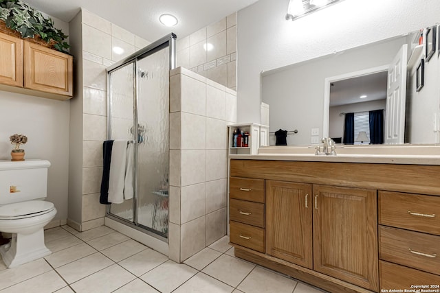 bathroom featuring vanity, a shower with shower door, tile patterned floors, and toilet